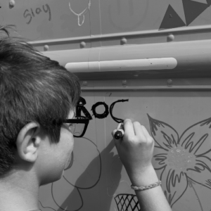 Child writing 'ROC'